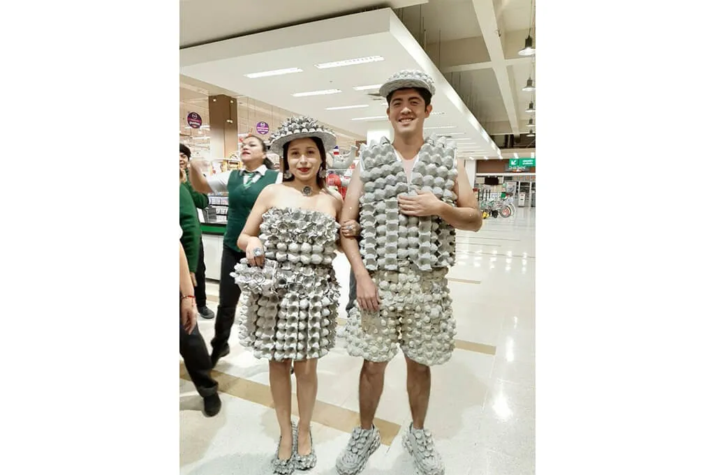 pareja con disfraces, vestido de mujer y camisa y bermudas de hombre, elaborados enteramente con cartones de huevos